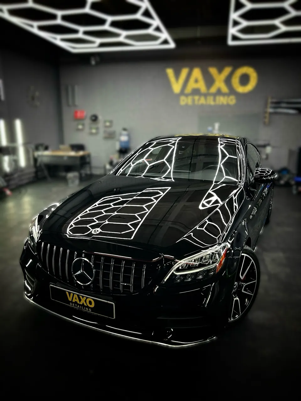Чёрный Mercedes C Coupe у стены VAXO, соты на капоте